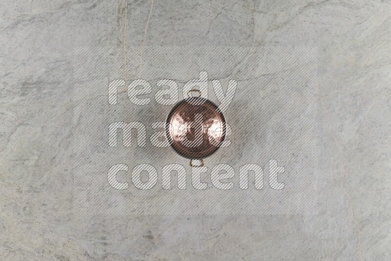 A small copper pot on grey marble background