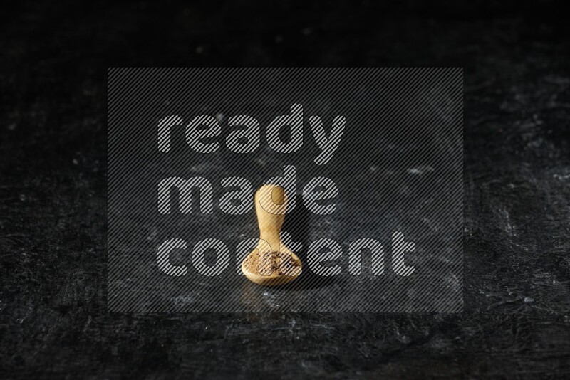 ملعقة خشبية ممتلئة ببودرة بهار الفلفل الحلو على خلفية سوداء