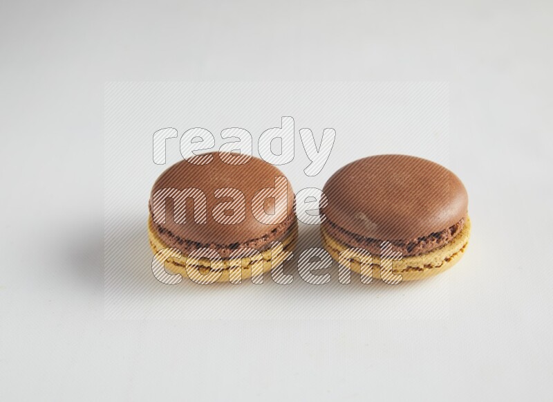 45º Shot of two Yellow and Brown Chai Latte macarons on white background