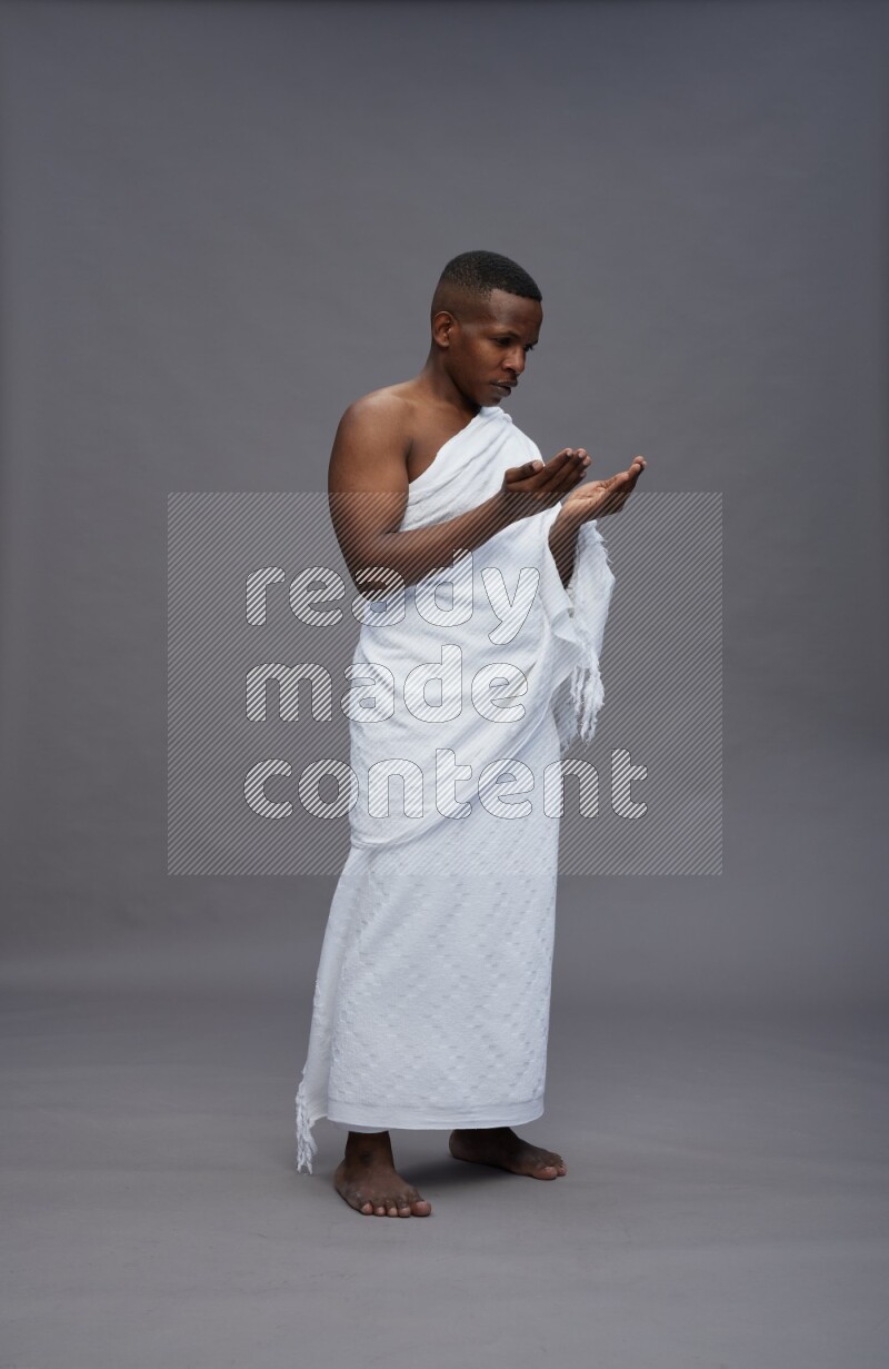A man wearing Ehram Standing dua'a on gray background
