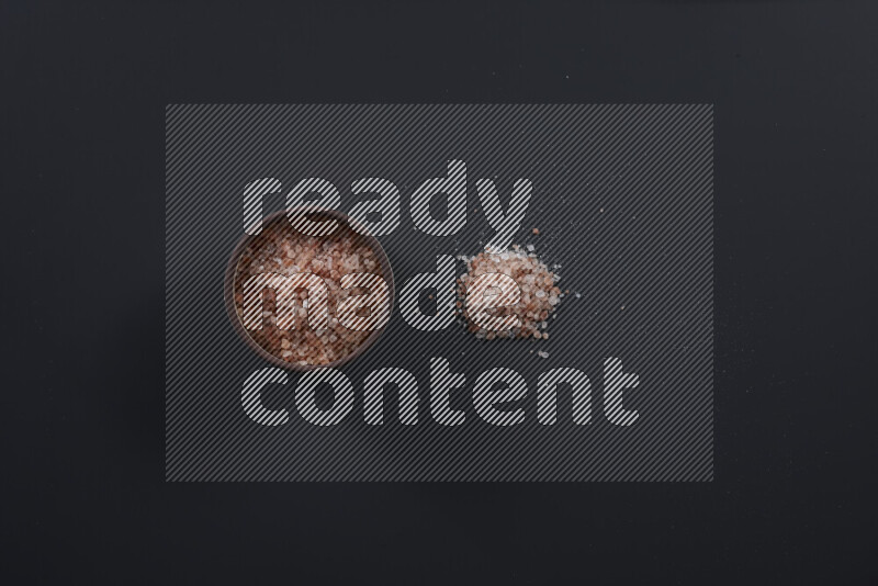 Pottery bowl full of fine himalayan salt and coarse himalayan salt on black background
