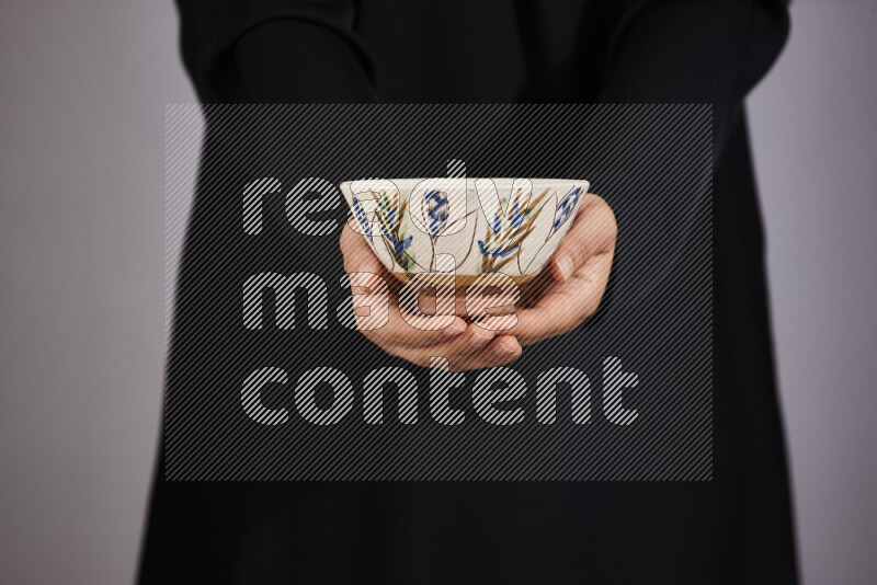 A woman in black abaya holding different pottery essentials in different positions