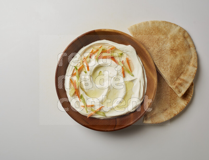 Lebnah garnished with sliced carrots & cucumber in a wooden plate on a white background
