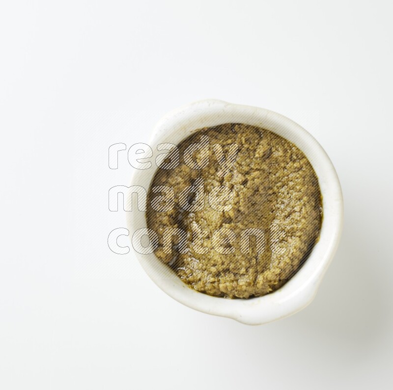medium off white pottery round bowl filled with pesto paste on a white counter top