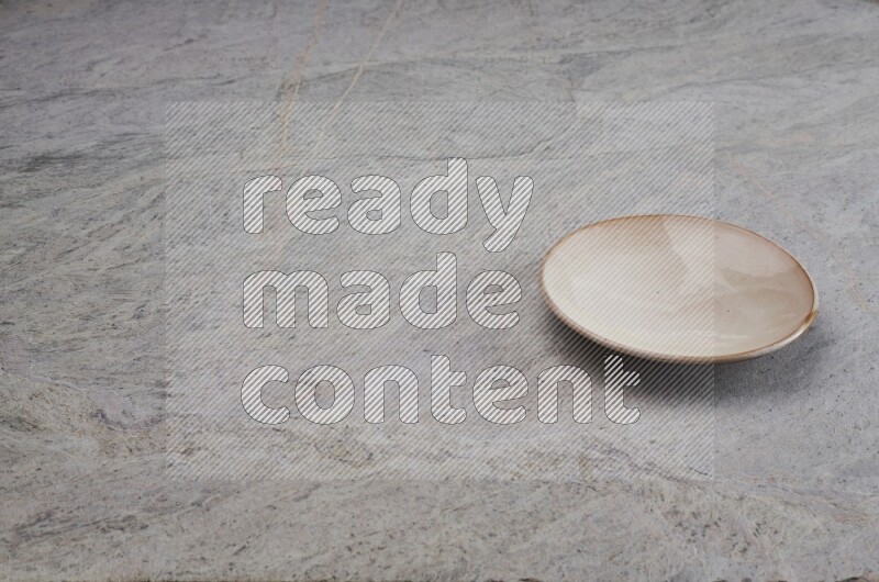 A beige pottery plate on grey marble background