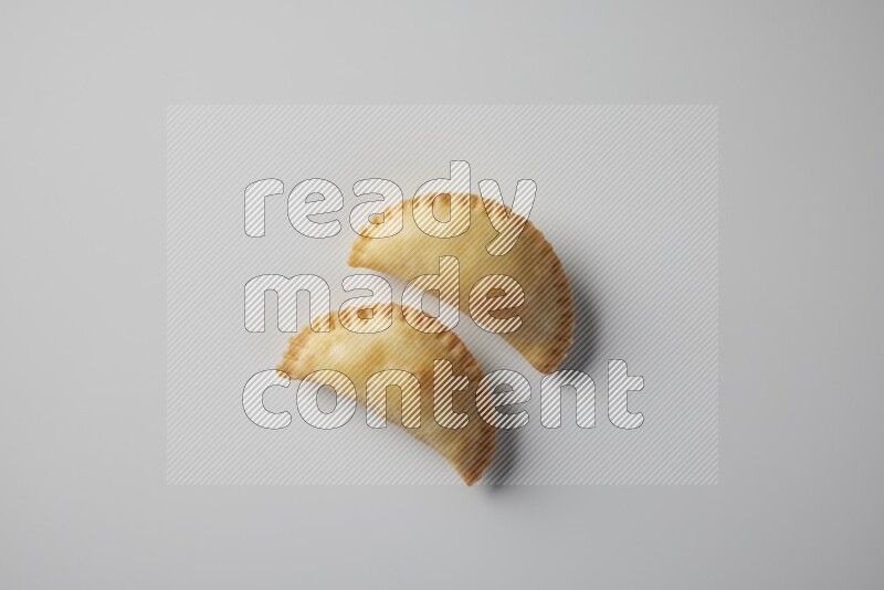 Two fried sambosa from a top angle on a white background