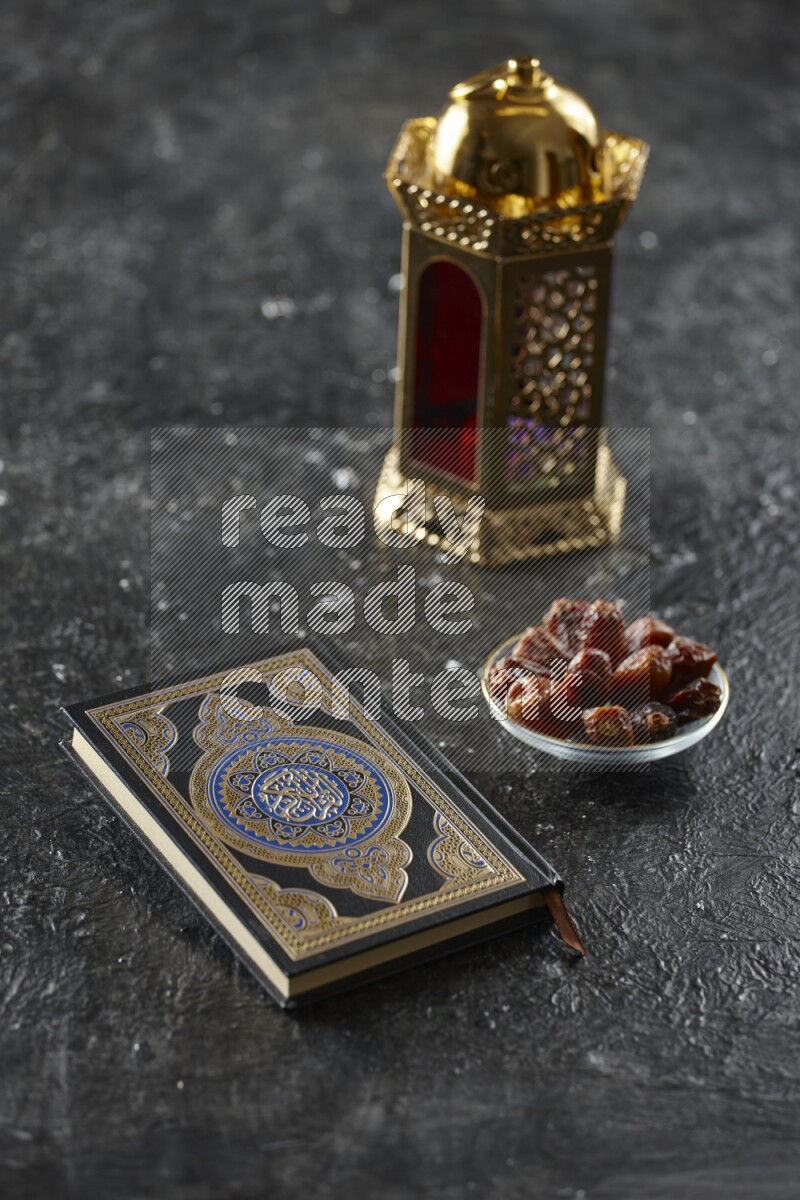 A golden lantern with different drinks, dates, nuts, prayer beads and quran on textured black background