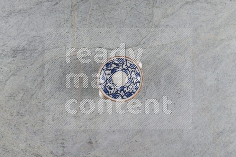 إناء فخاري متعدد الألوان مع غطائه على خلفية من الرخام الرمادي