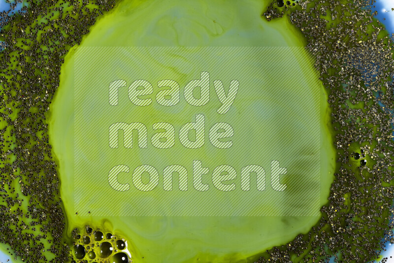 A close-up of sparkling gold glitter scattered on swirling blue and green background