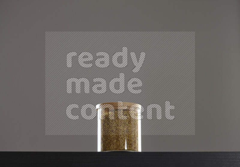Coarse bulgur in a glass jar on black background