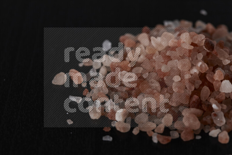 A bunch of coarse himalayan salt crystals on black background