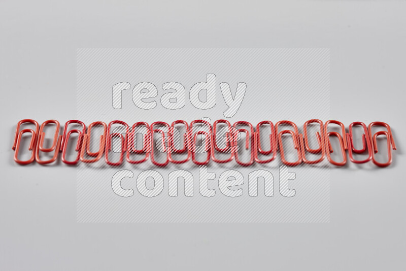 Red paper clips isolated on a grey background