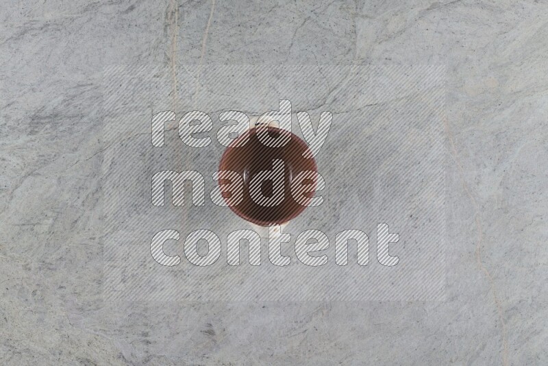 A multicolored pottery pot with its lid on grey marble background