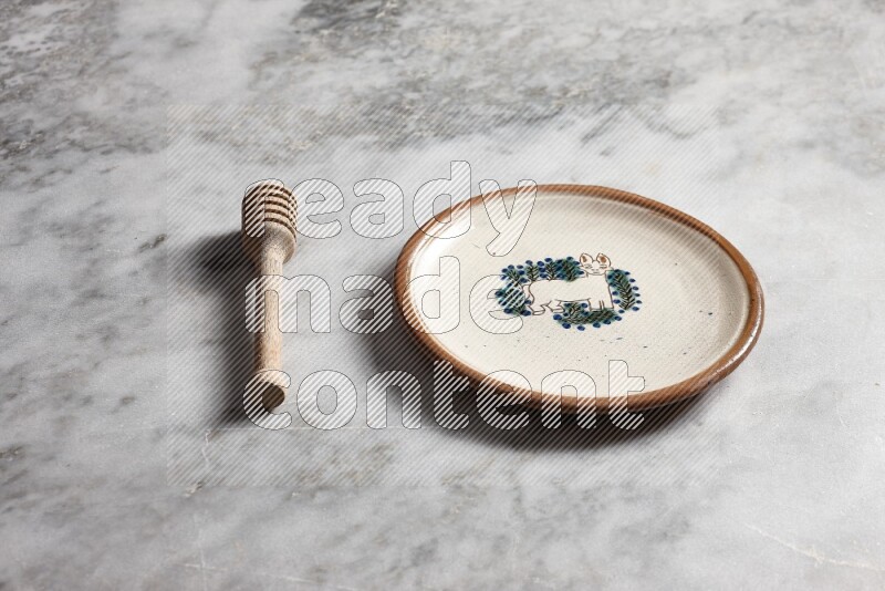 Decorative pottery plate with wooden honey dipper on the side on grey marble background