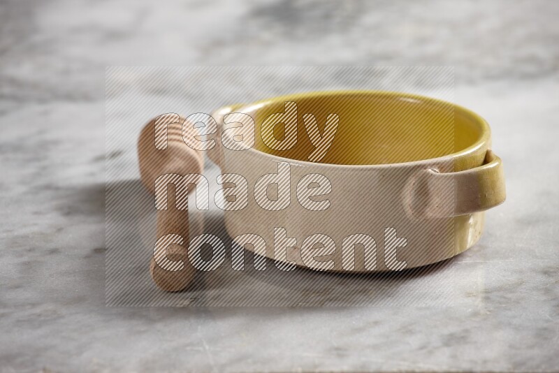 Multicolored pottery bowl with wooden honey dipper on the side on grey marble background