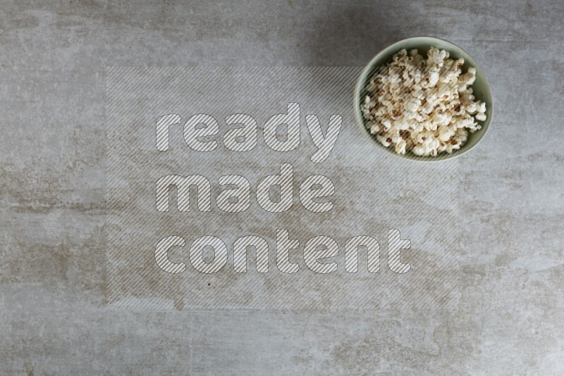 popcorn in green bowl on a grey textured countertop