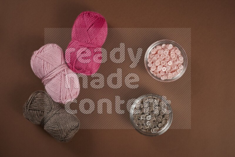 A pink collection of sewing and tailoring tools arranged on a brown background