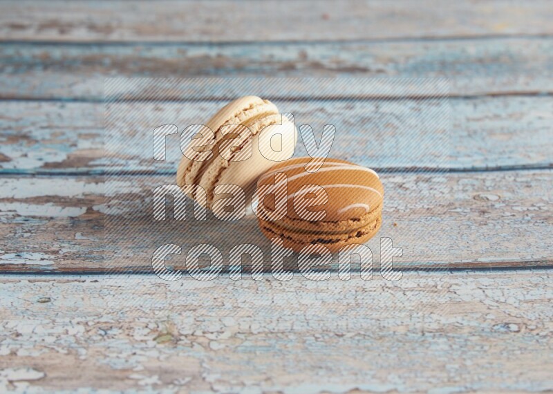 45º Shot of of two assorted Brown Irish Cream, and White Caramel fleur de sel macarons on light blue background