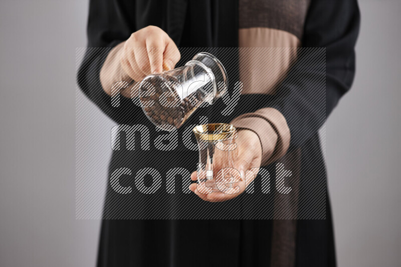 Woman in abaya holding different kinds of coffee beans in different positions