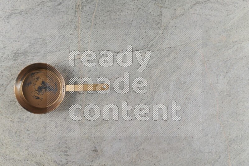 A small copper pan on grey marble background