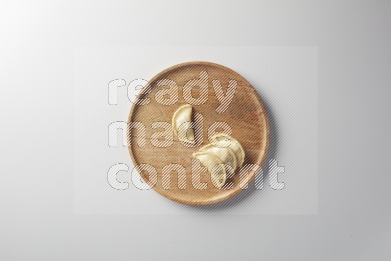 Four Sambosas on a wooden round plate on a white background
