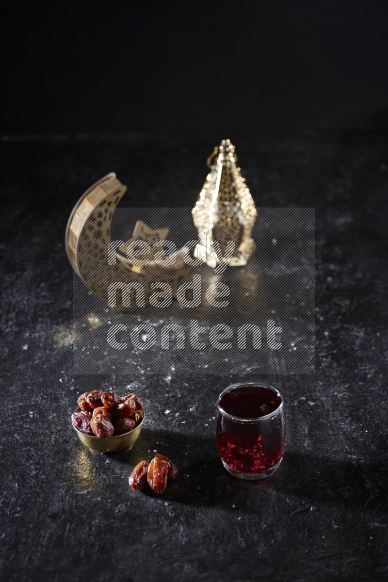 Dates in a metal bowl with Hibiscus beside golden lanterns in a dark setup