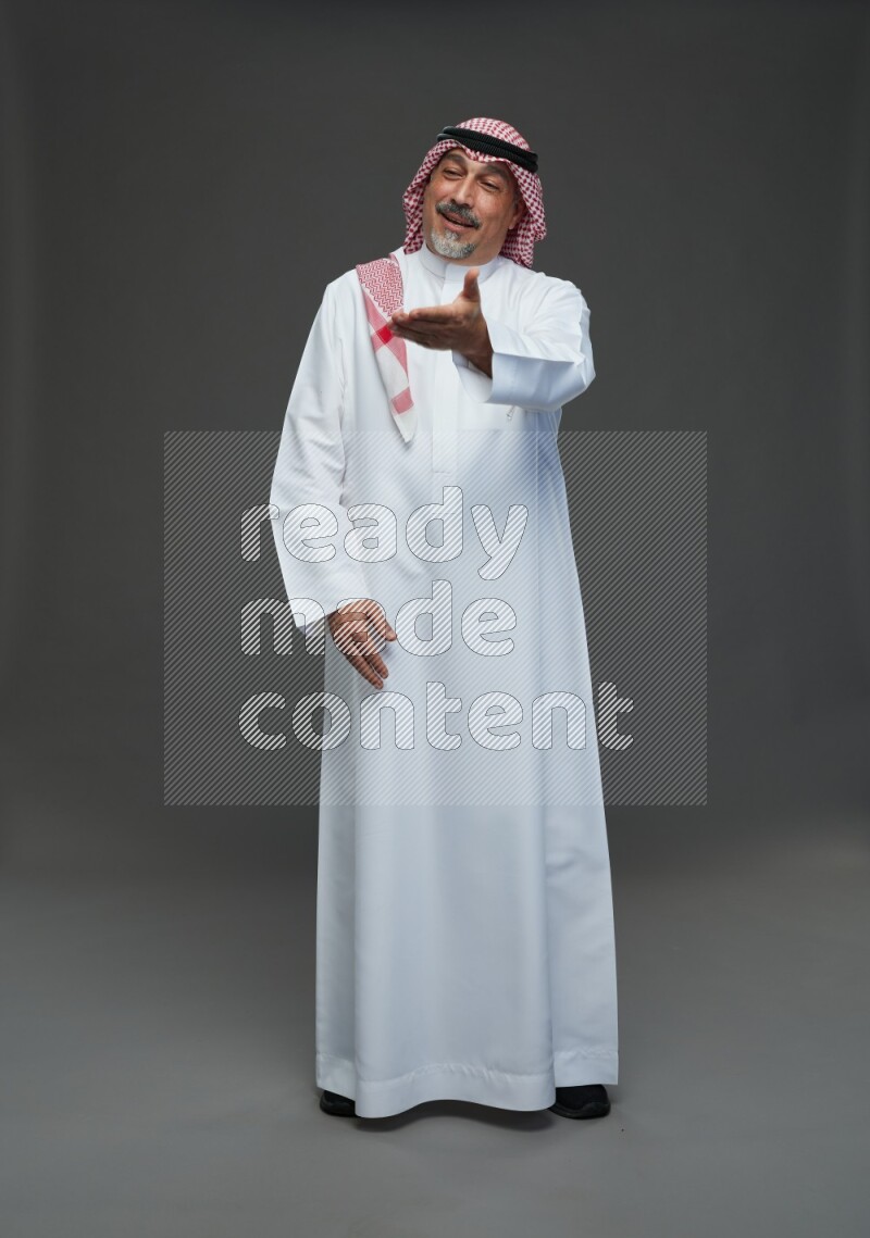 Saudi man with shomag Standing Interacting with the camera on gray background