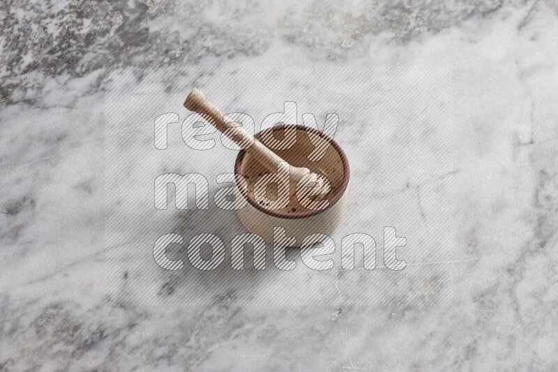 Beige Pottery oven bowl with wooden honey handle on the side with grey marble flooring, 65 degree angle