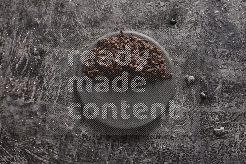 Cloves on a black plate on textured black background