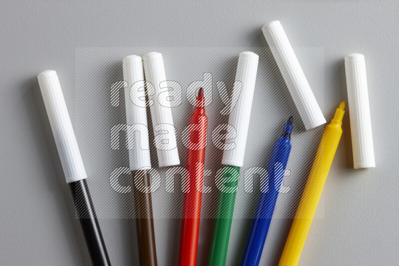 An arrangement of coloring pens in different colors on grey background