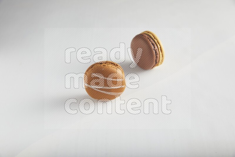 45º Shot of of two assorted Brown Irish Cream, and Yellow, and Brown Chai Latte macarons on white background
