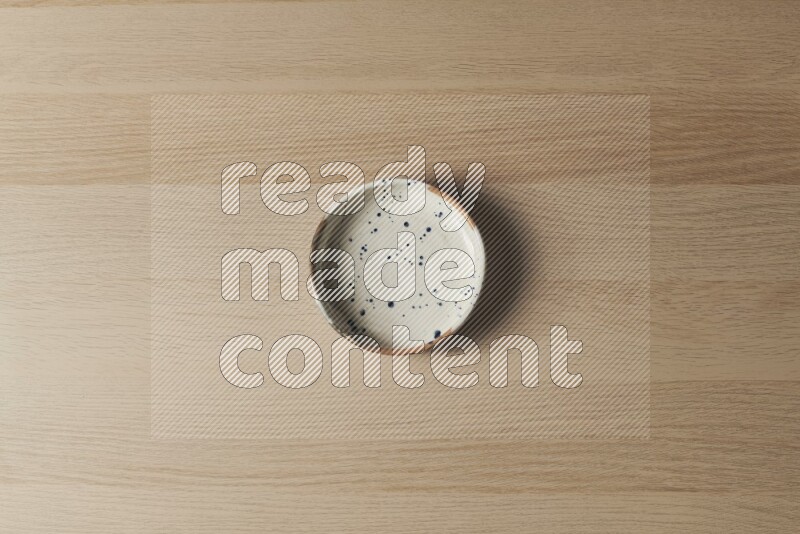 A multicolored pottery bowl on light wooden background