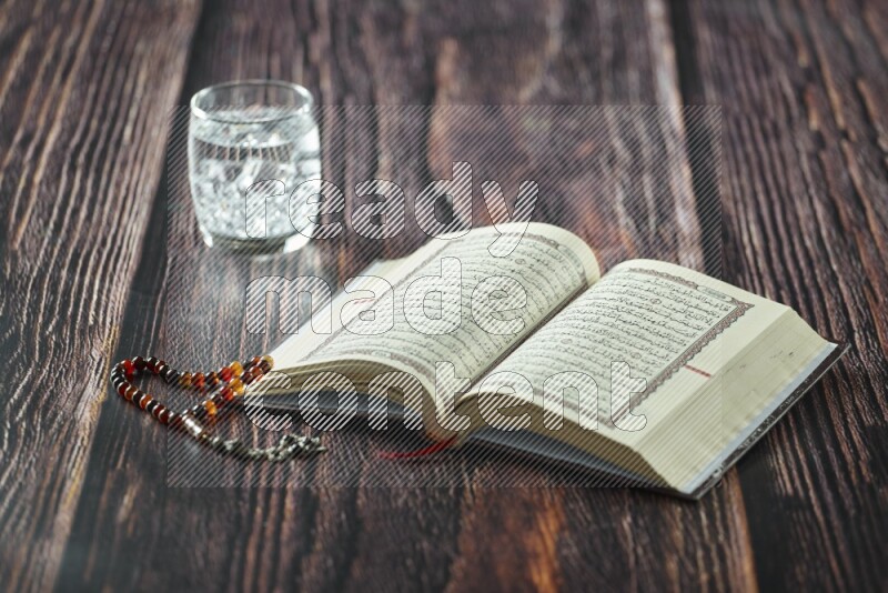 Quran with dates, prayer beads and different drinks all placed on wooden background