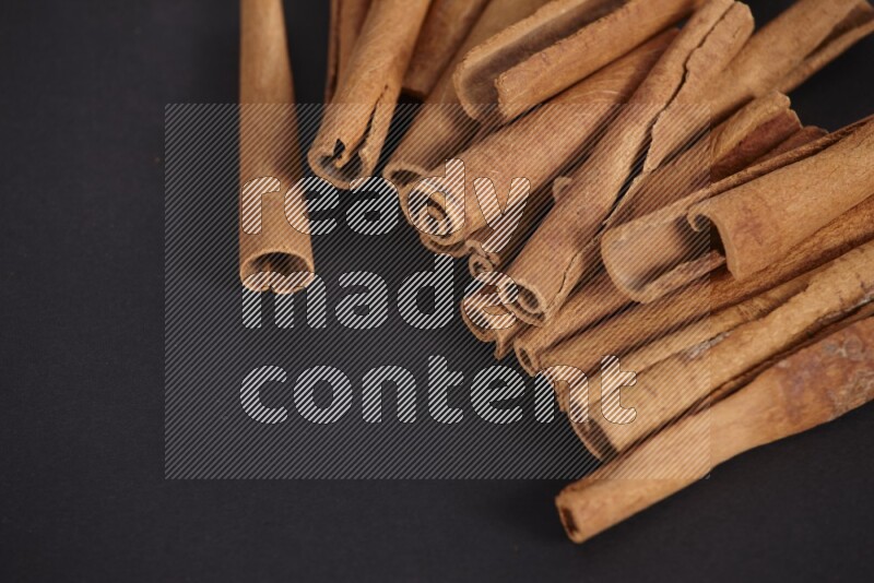 Cinnamon sticks stacked on black flooring