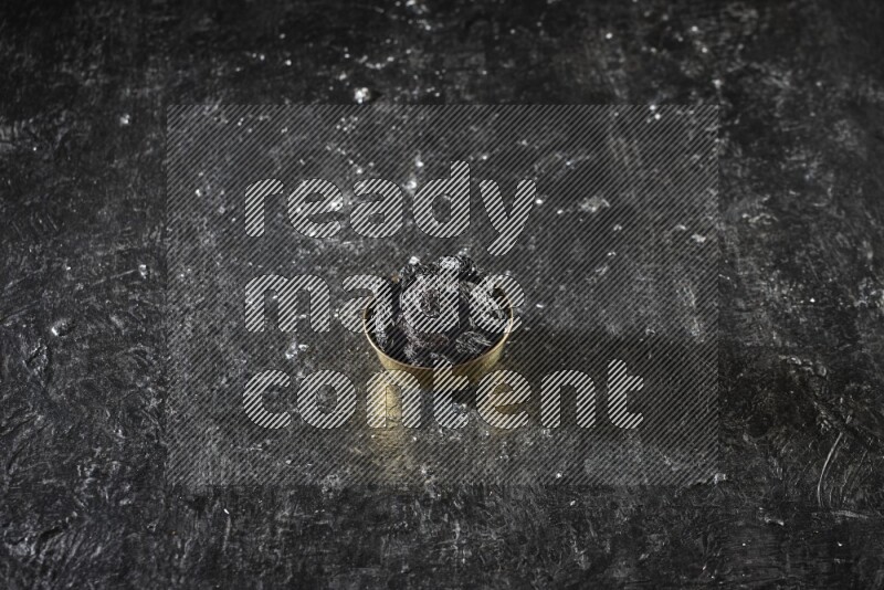 Dried fruits in a metal bowl in a dark setup