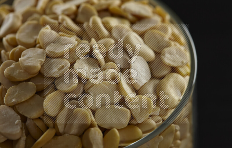 Crushed beans in a glass jar on black background