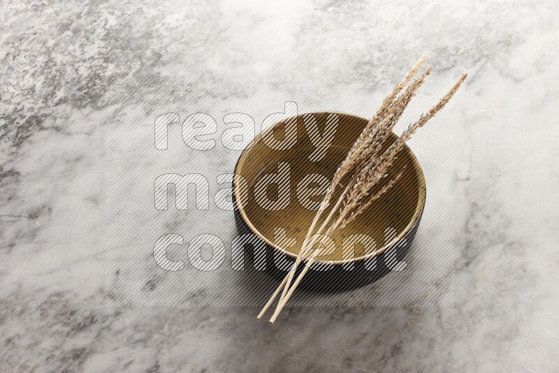 Wheat stalks on multicolored pottery oven plate on grey marble background