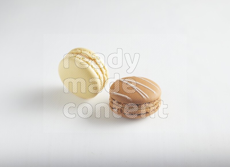 45º Shot of of two assorted Brown Irish Cream, and Yellow Vanilla macarons on white background