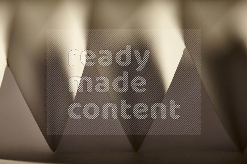 A close-up abstract image showing sharp geometric paper folds in warm gradients