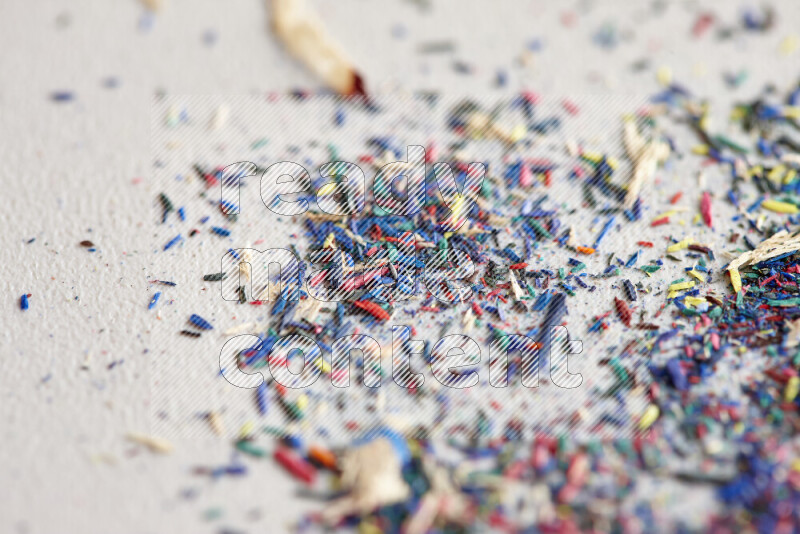 This image showcases a vibrant multicolored pencil shavings scattered on grey background