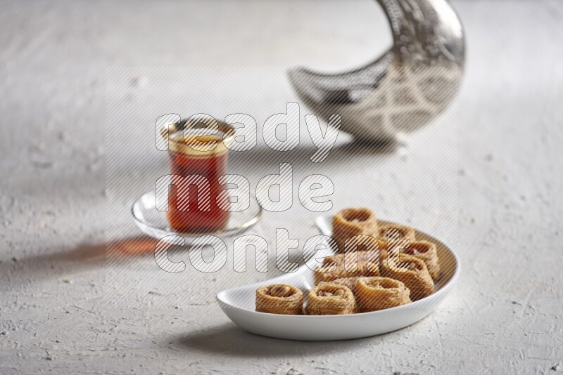 Konafa in a pottery plate with lantern and tea in a light setup