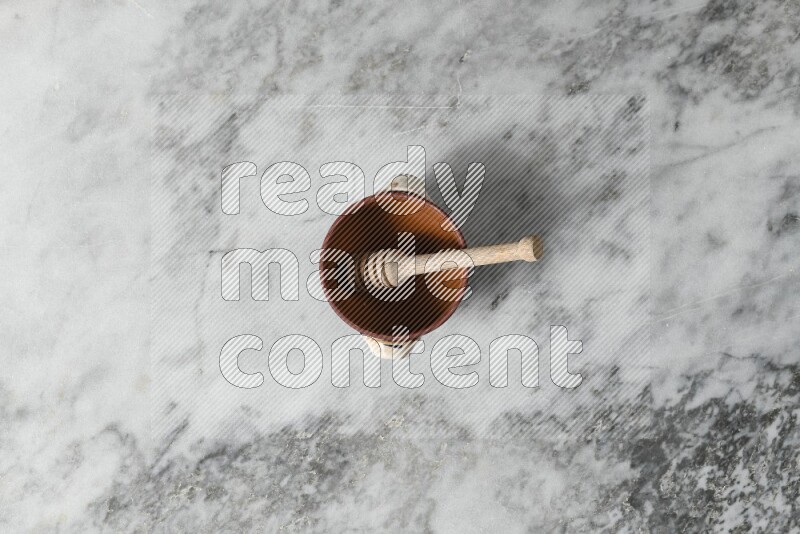 Decorative Pottery Pot with wooden honey handle in it, on grey marble flooring, Top View