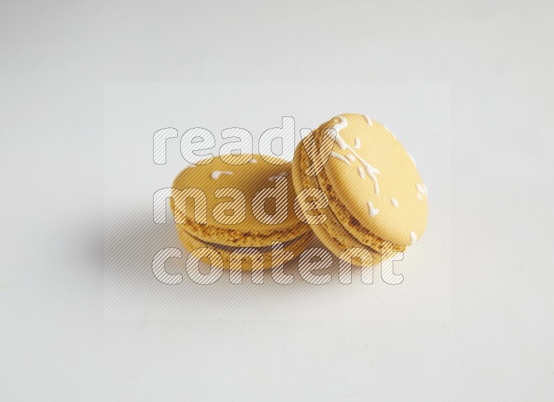 45º Shot of two Yellow Piña Colada macarons on white background