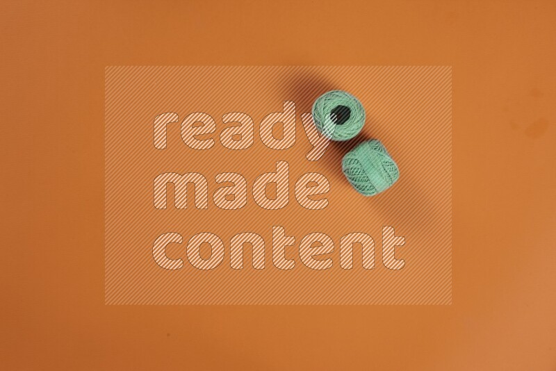 A green and orange collection of sewing and tailoring tools arranged on a orange background