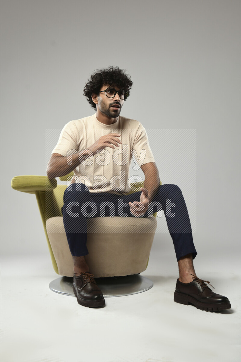 A man wearing casual sitting on a chair making a hand gesture on white background