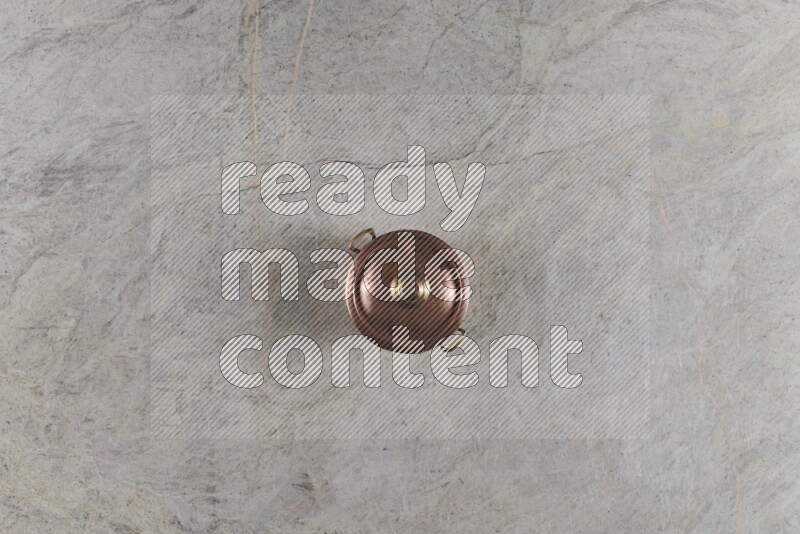 A small copper pot on grey marble background