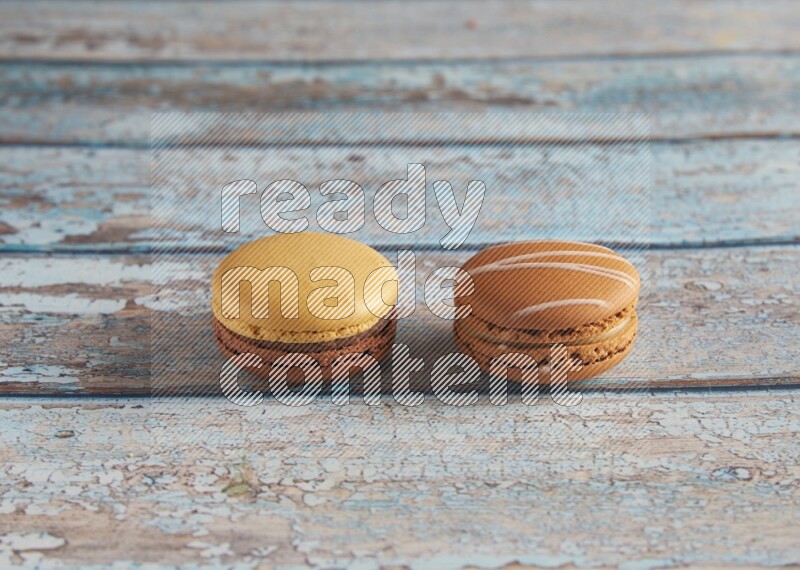 45º Shot of of two assorted Brown Irish Cream, and Yellow, and Brown Chai Latte macarons  on light blue background