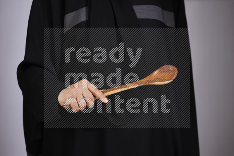 A woman in black abaya holding different wooden essentials in different positions