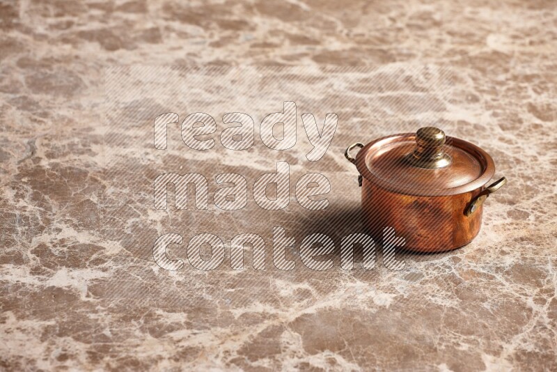 A small copper pot on beige marble background
