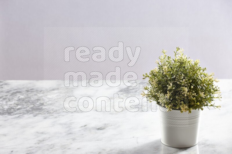 Artificial plant in white pot on grey marble background
